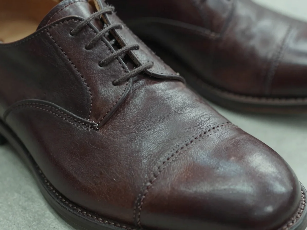 Tight close-up of a leather shoe upper being stitched, thread lin